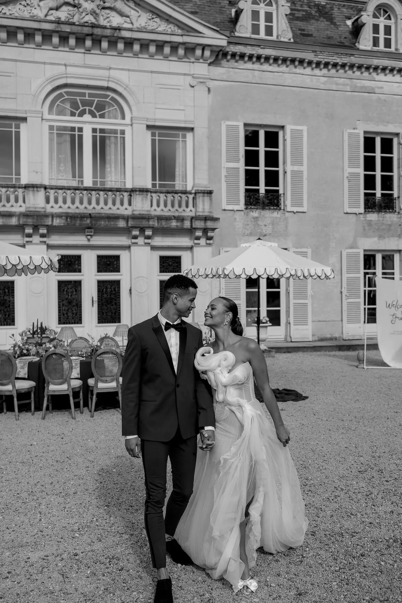 Schwarz-Weiß Portrait des verliebten Brautpaares vor dem Chateau de Varennes mit Hochzeitsempfang im Hintergrund